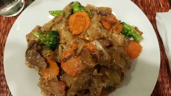Kuay Tiew Pad Sie Eew (Pad Sie Eew) — Stir-fried wide rice noodles with your choice of meat, broccoli, carrots and egg in slightly sweet soy sauce.